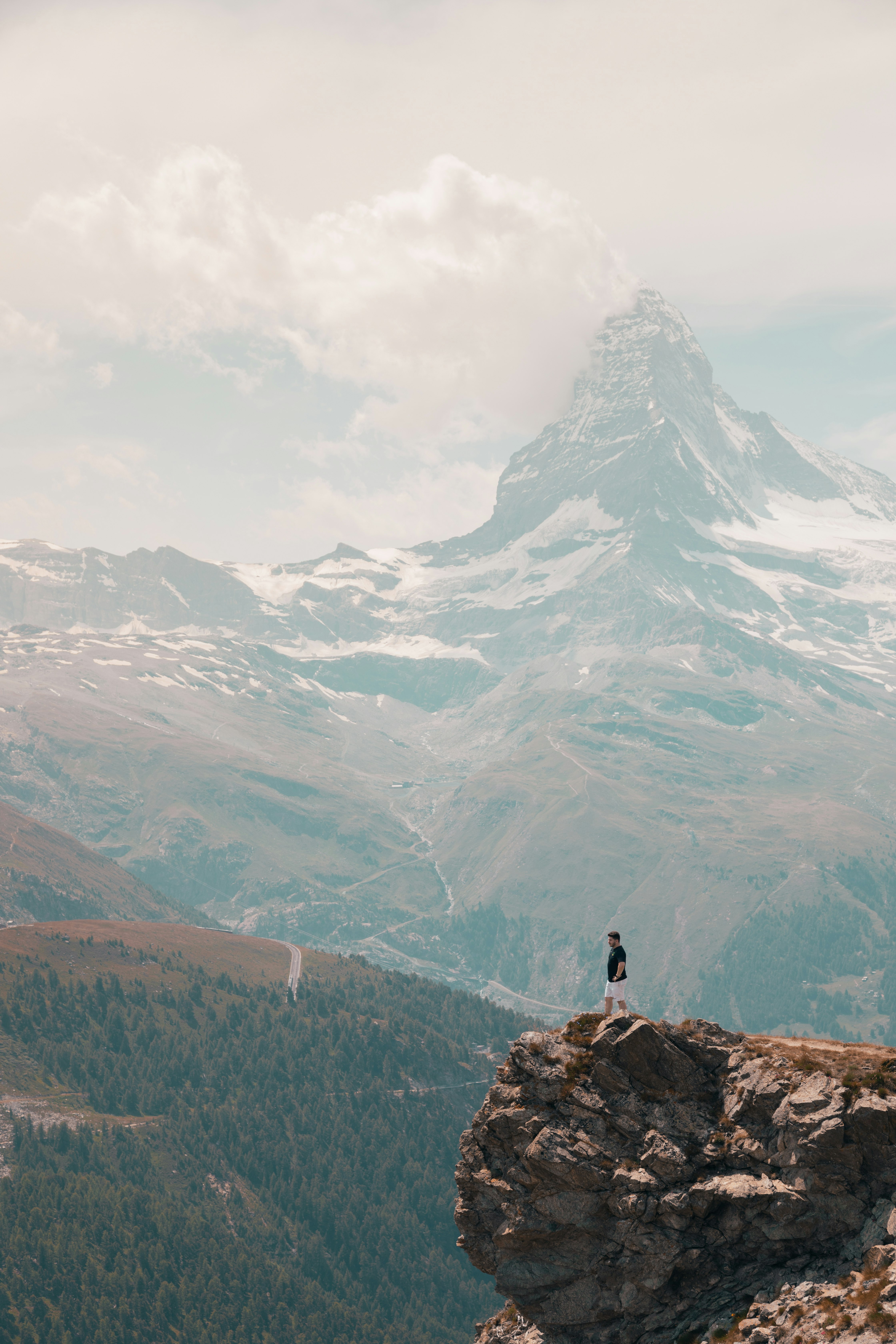 person standing on rock near snow covered mountain during daytime